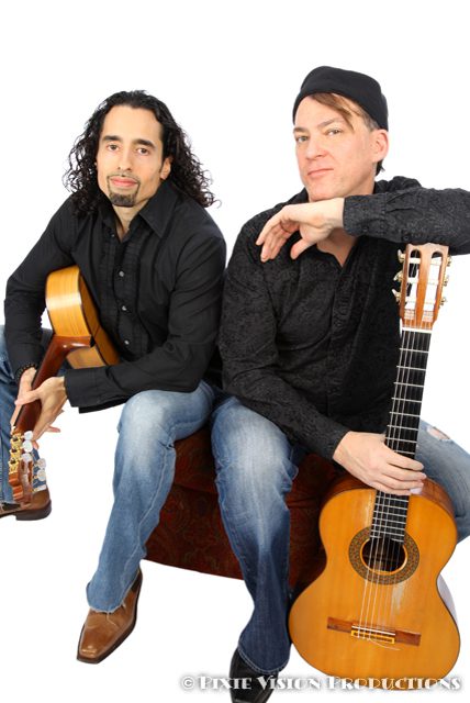 Two men sitting with acoustic guitars.