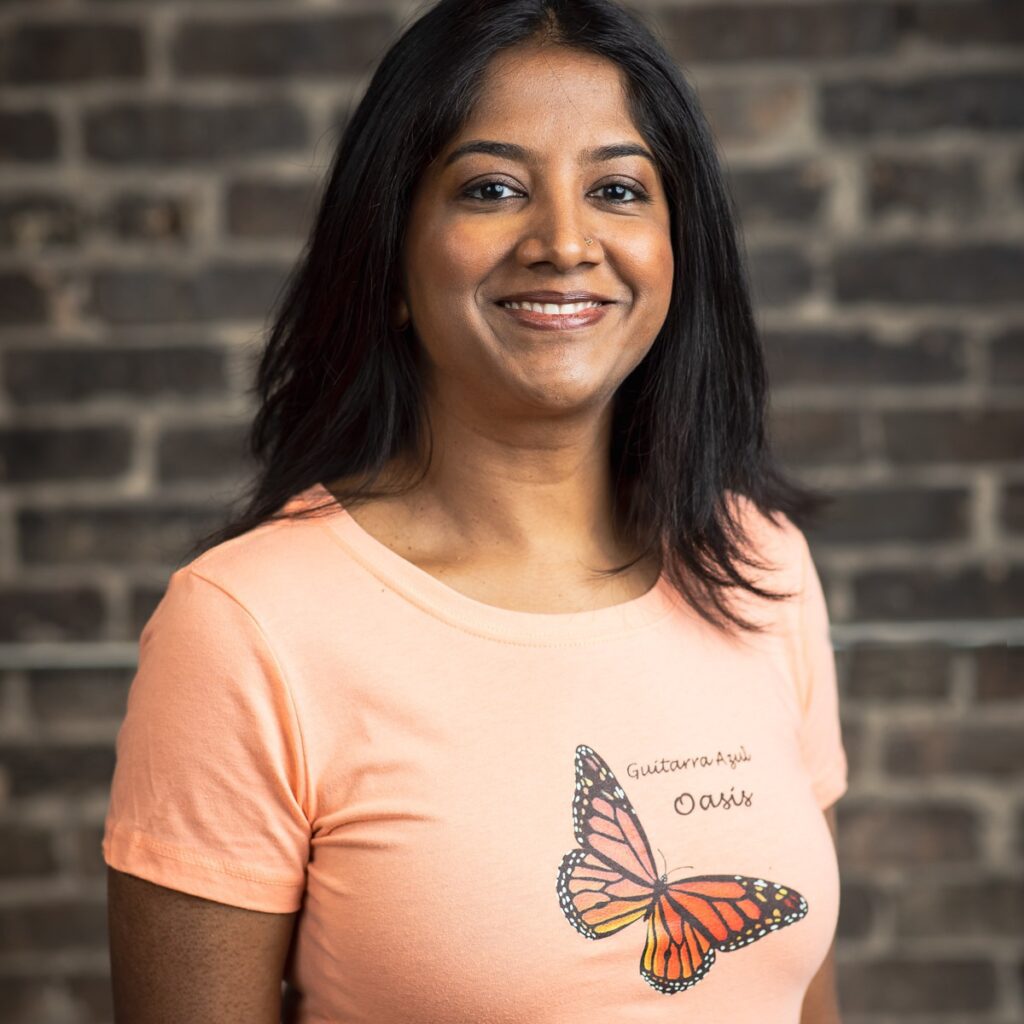 Smiling woman in orange butterfly shirt.