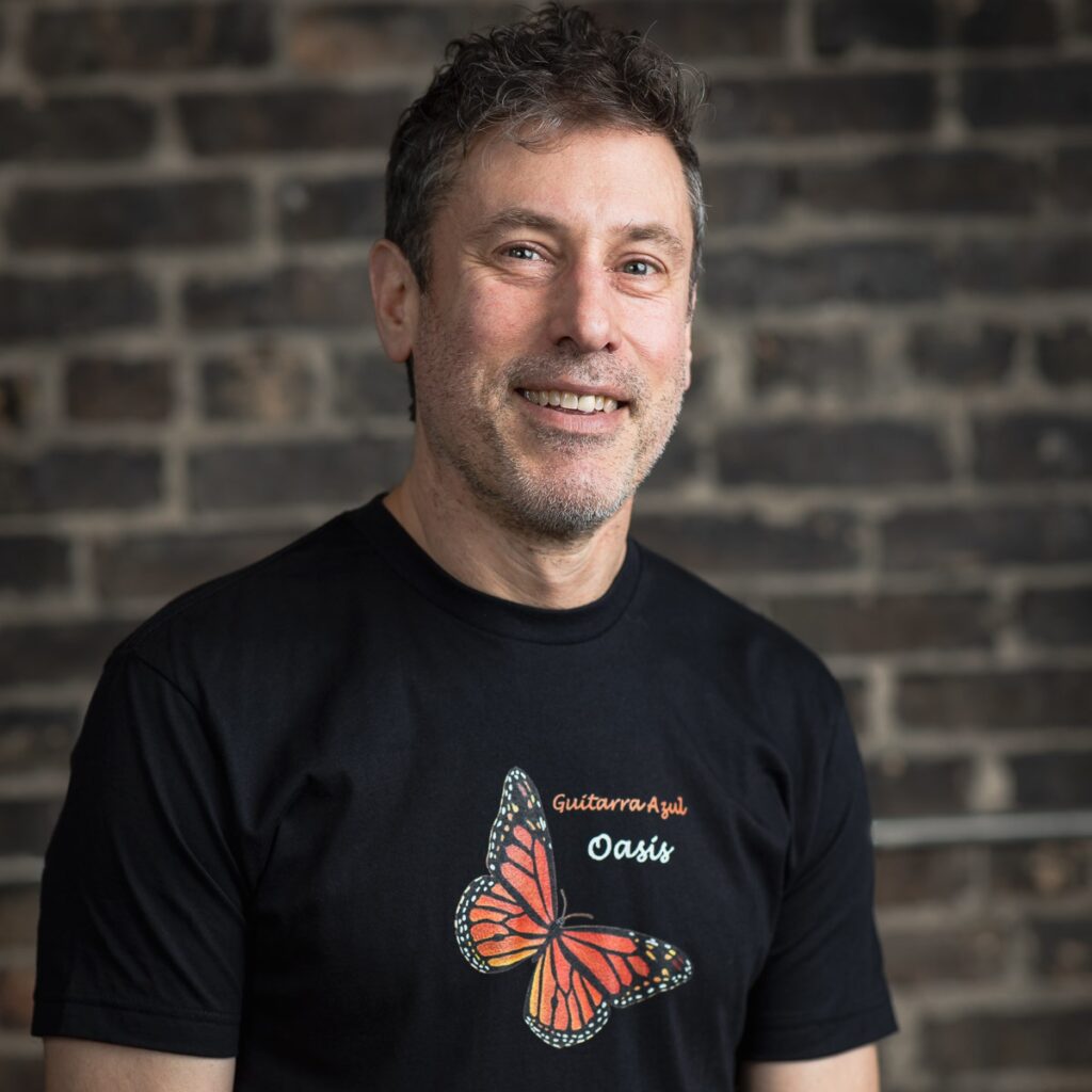 Man smiling, wearing butterfly t-shirt.