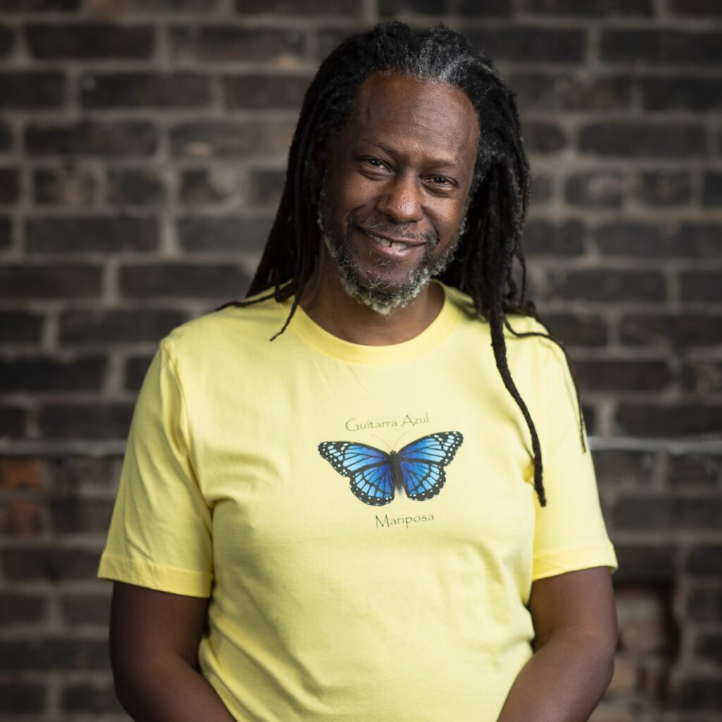 Man in yellow butterfly shirt, smiling broadly.