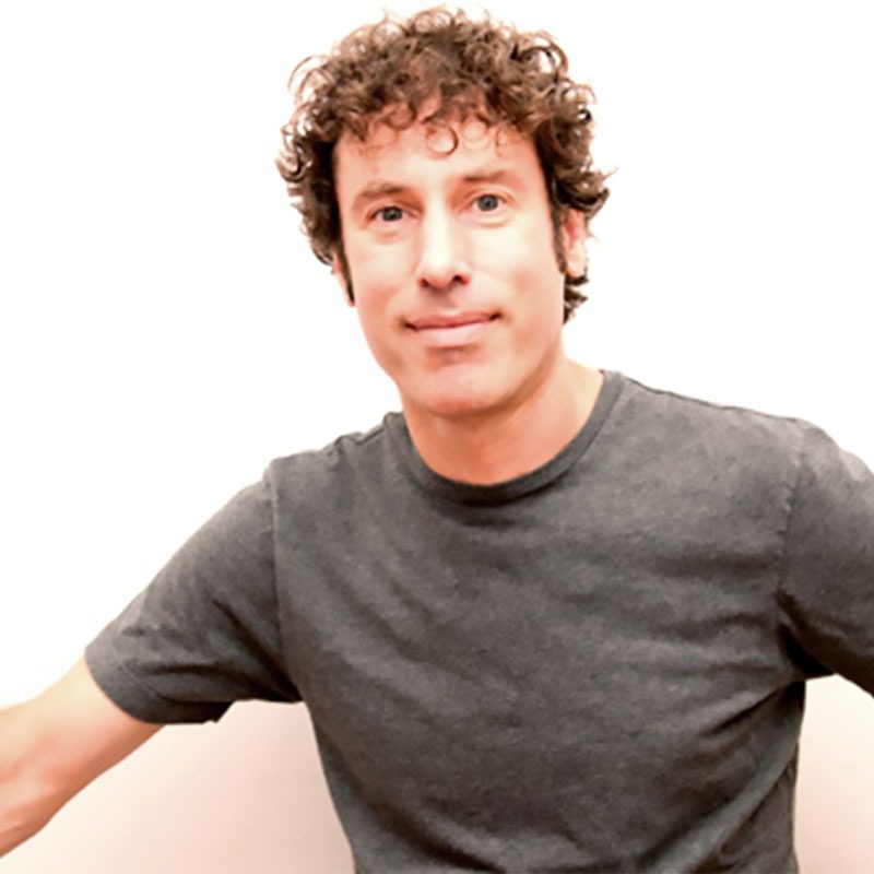 Man with curly hair wearing gray shirt.
