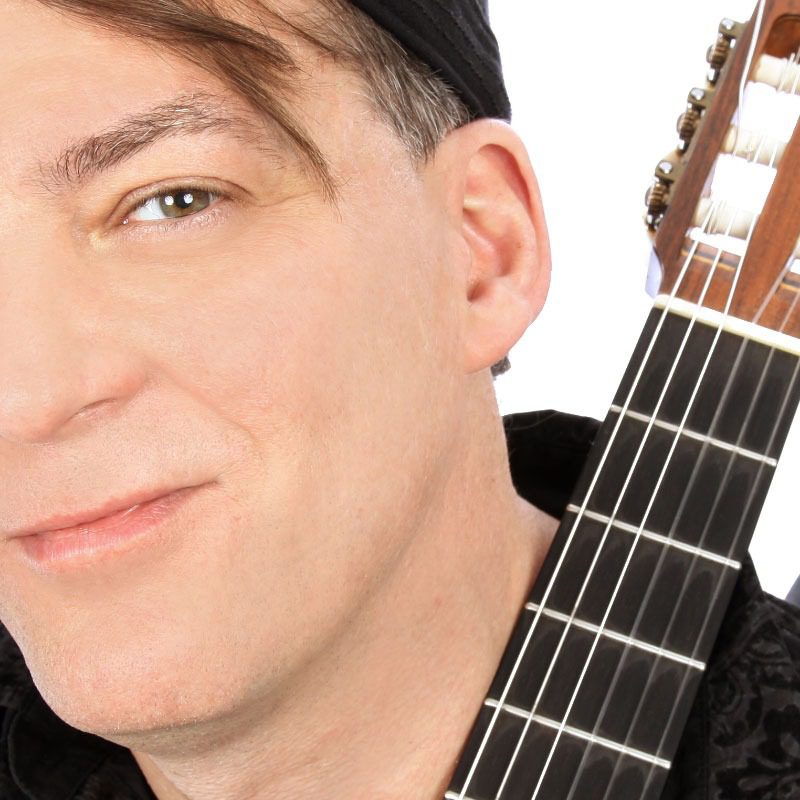 Man with a guitar, wearing a hat.