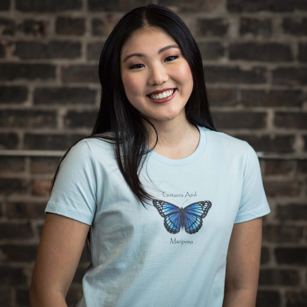 Smiling woman wearing butterfly design shirt.