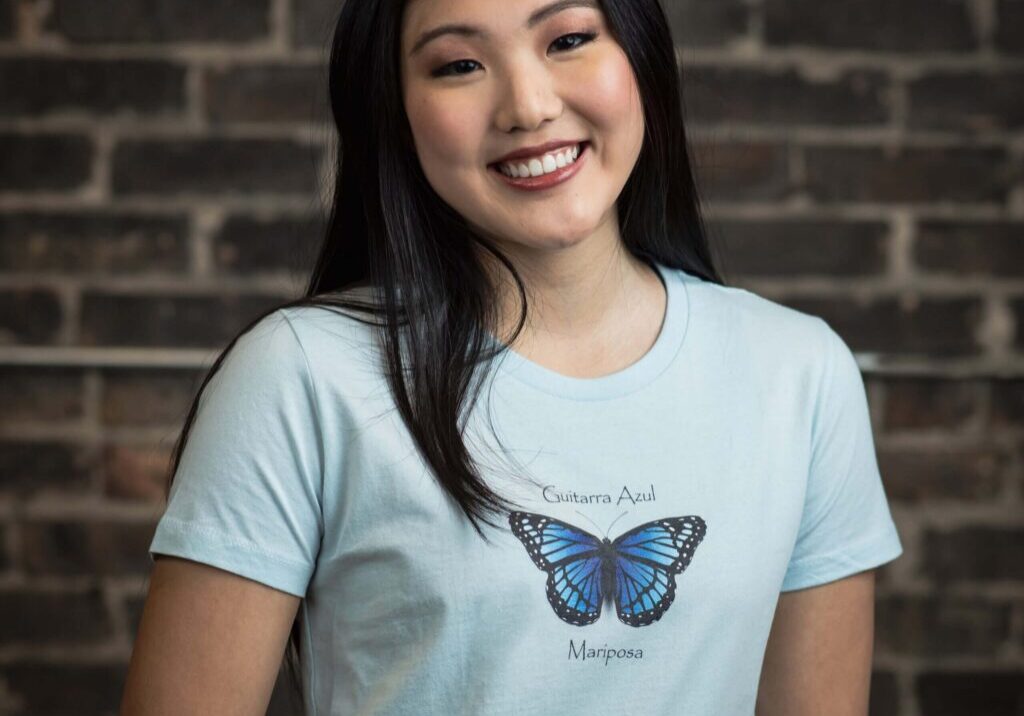 Smiling woman wearing butterfly design shirt.